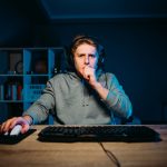 Focused,Gamer,In,A,Headset,Sits,At,A,Table,At